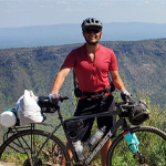 Ricky P. standing with his bicycle. Mountains are in the background